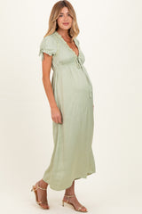 woman wearing a light green short sleeve maternity maxi dress with a tie detail and a visible baby bump