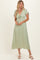 woman wearing a light green maxi dress with short sleeves and lace detailing, posing with hands placed on her waist