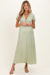 woman wearing a sage green maternity maxi dress with lace details and short sleeves, showcasing her baby bump