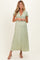 woman wearing a sage green maternity maxi dress with lace details and short sleeves, showcasing her baby bump