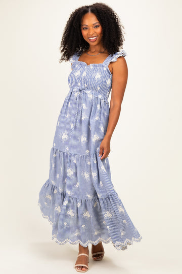 woman wearing a blue and white striped floral maxi dress with ruffled straps and tiered skirt