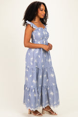 woman wearing a blue and white striped maxi dress with ruffle straps and floral details