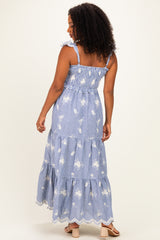 woman wearing a blue and white striped maxi dress with floral prints and ruffled straps seen from the back