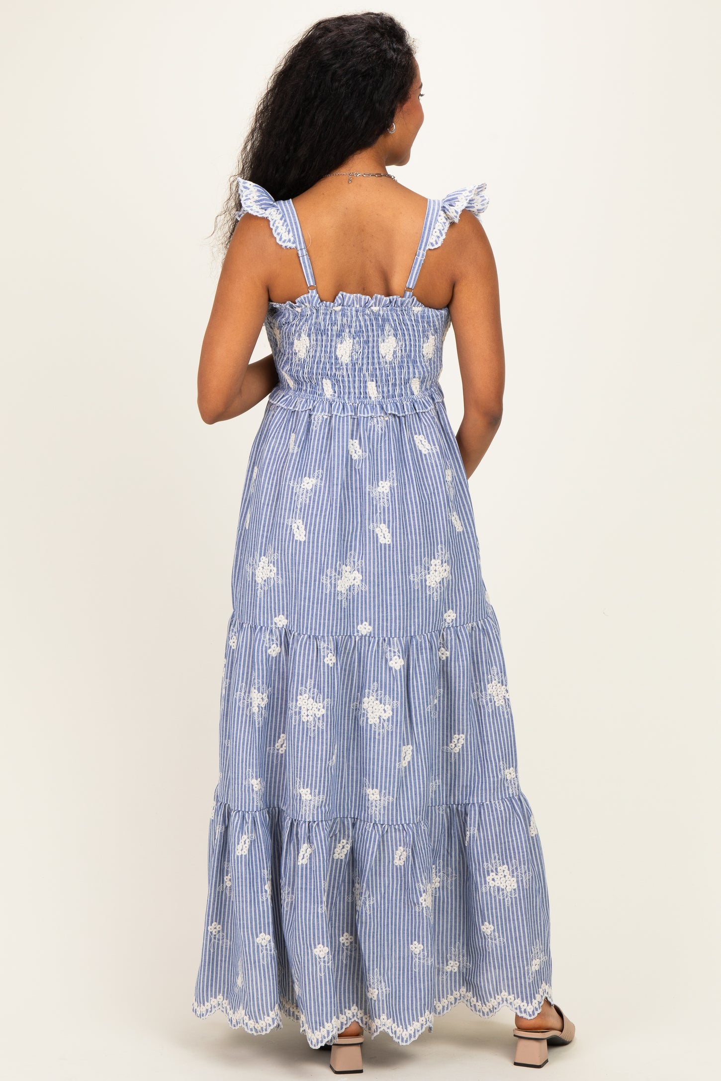 woman wearing a blue and white striped maternity maxi dress with ruffle straps and floral print from the back
