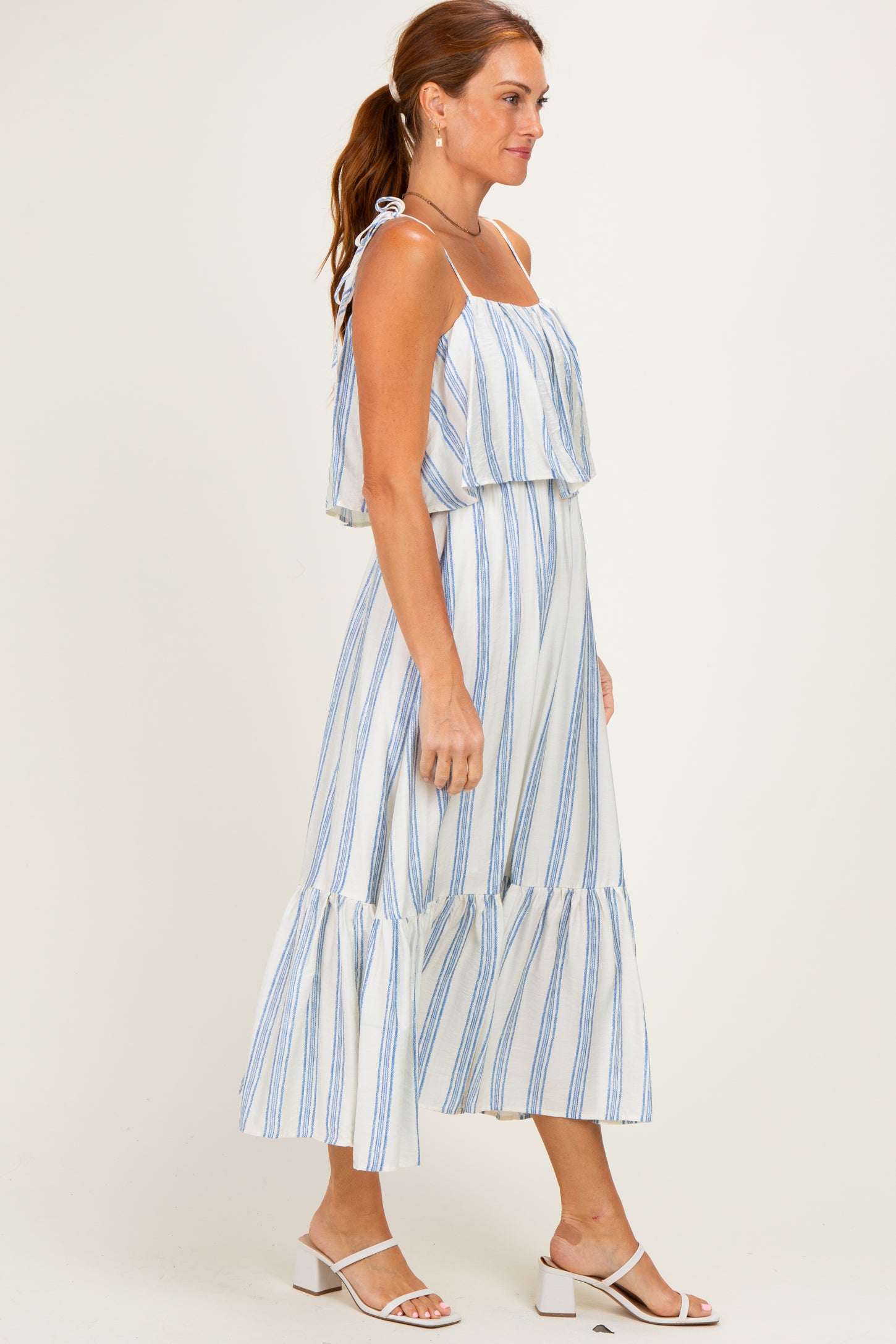woman wearing a white and blue striped off-the-shoulder maxi dress with ruffle hem and spaghetti straps