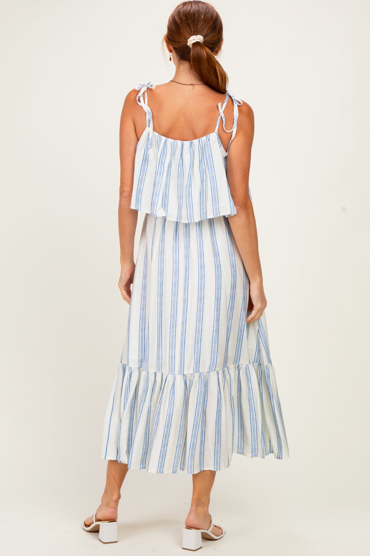 woman wearing a white and blue striped tiered maxi dress with tie straps and a ruffled hemline