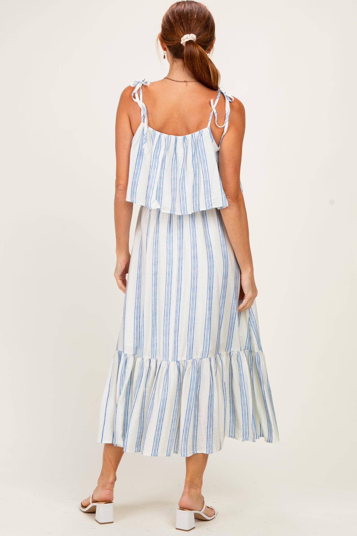 woman wearing a white and blue striped tiered maxi dress with tie straps and a ruffled hemline