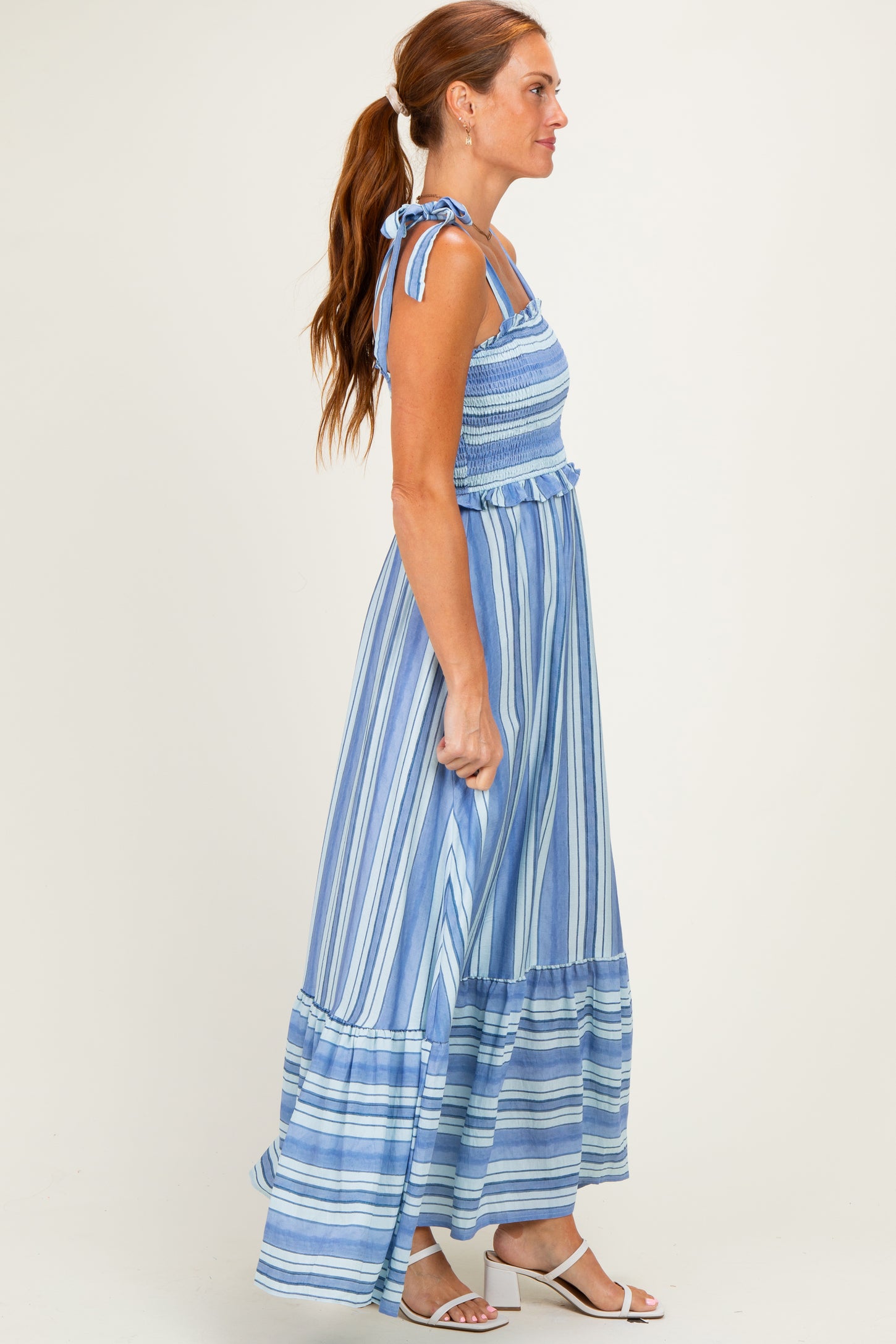 woman wearing a blue striped maxi dress with tie shoulder straps and a ruffled hem