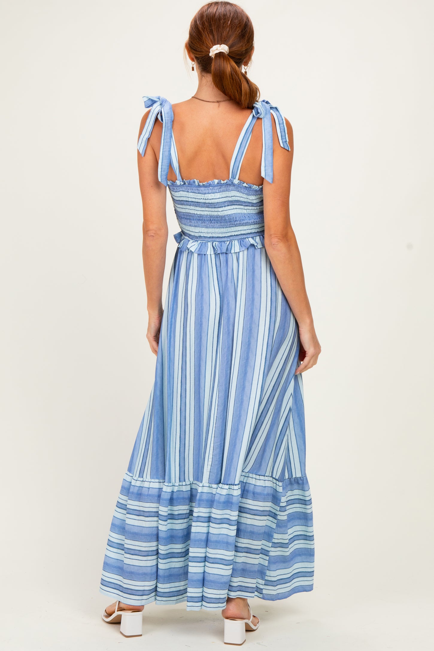 woman wearing a blue and white striped maxi dress with tie straps and a smocked bodice, viewed from the back