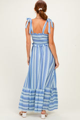 woman wearing a blue and white striped maxi dress with tie straps and a smocked bodice, viewed from the back