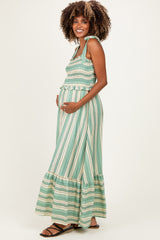 woman wearing a green and white striped maternity maxi dress with smocked bodice and ruffled hem, showing her baby bump