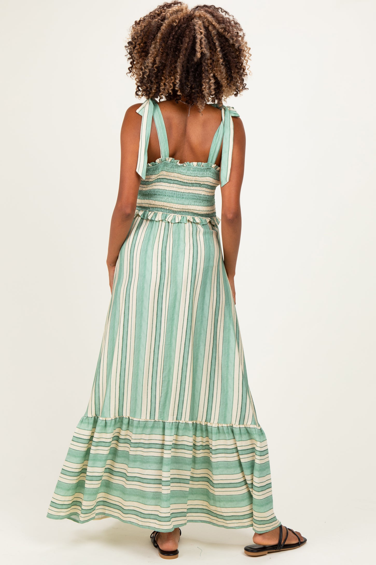 woman wearing a green and white striped maternity maxi dress with adjustable straps and a tiered skirt