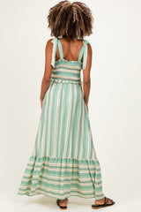woman wearing a green and white striped maternity maxi dress with adjustable straps and a tiered skirt