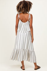 woman wearing a striped maternity maxi dress with a tiered skirt and tie straps, showing her back and long curly hair