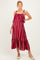 woman wearing a burgundy striped maternity maxi dress with ruffle straps and a tiered hem, showcasing her baby bump