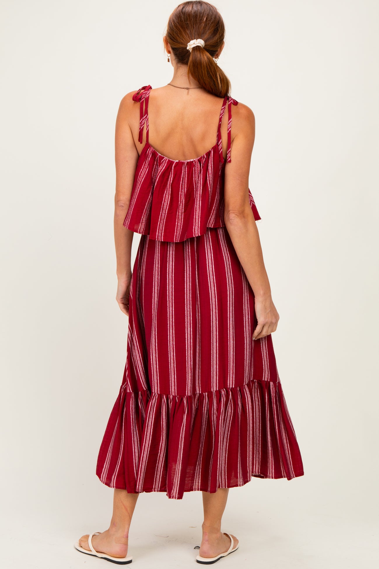 woman wearing a red striped maxi dress with ruffled straps and a tiered hem, shown from the back