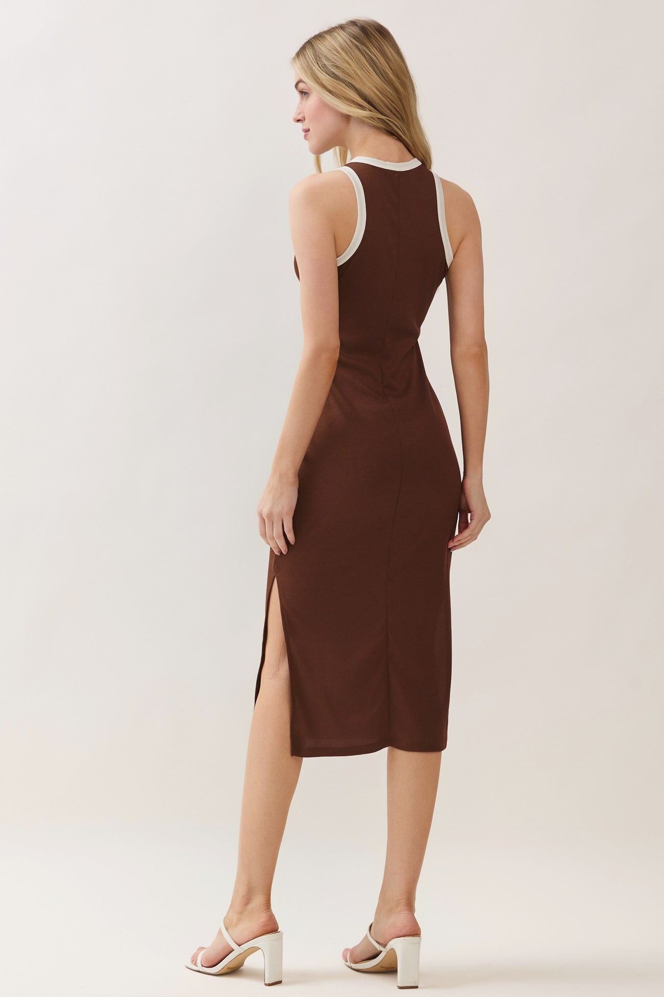 woman wearing a brown sleeveless midi dress with side slits and contrasting white trim