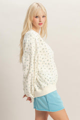 woman wearing a cream floral printed oversized sweatshirt and a blue mini skirt