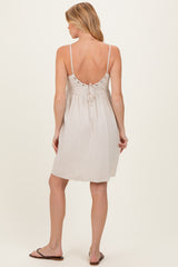 woman wearing a light beige maternity sundress with adjustable straps and button details at the back