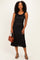 woman wearing a black sleeveless lace midi dress and holding a brown handbag
