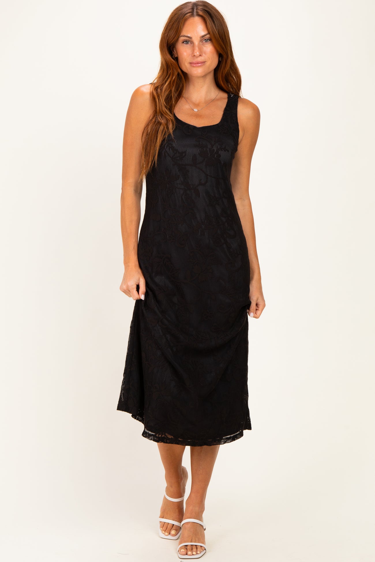 woman wearing a black spaghetti strap midi dress with a floral pattern and a relaxed fit