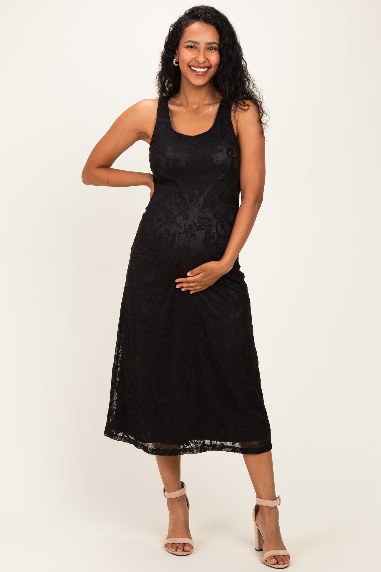 woman wearing a black lace maternity dress with a fitted silhouette and a visible baby bump