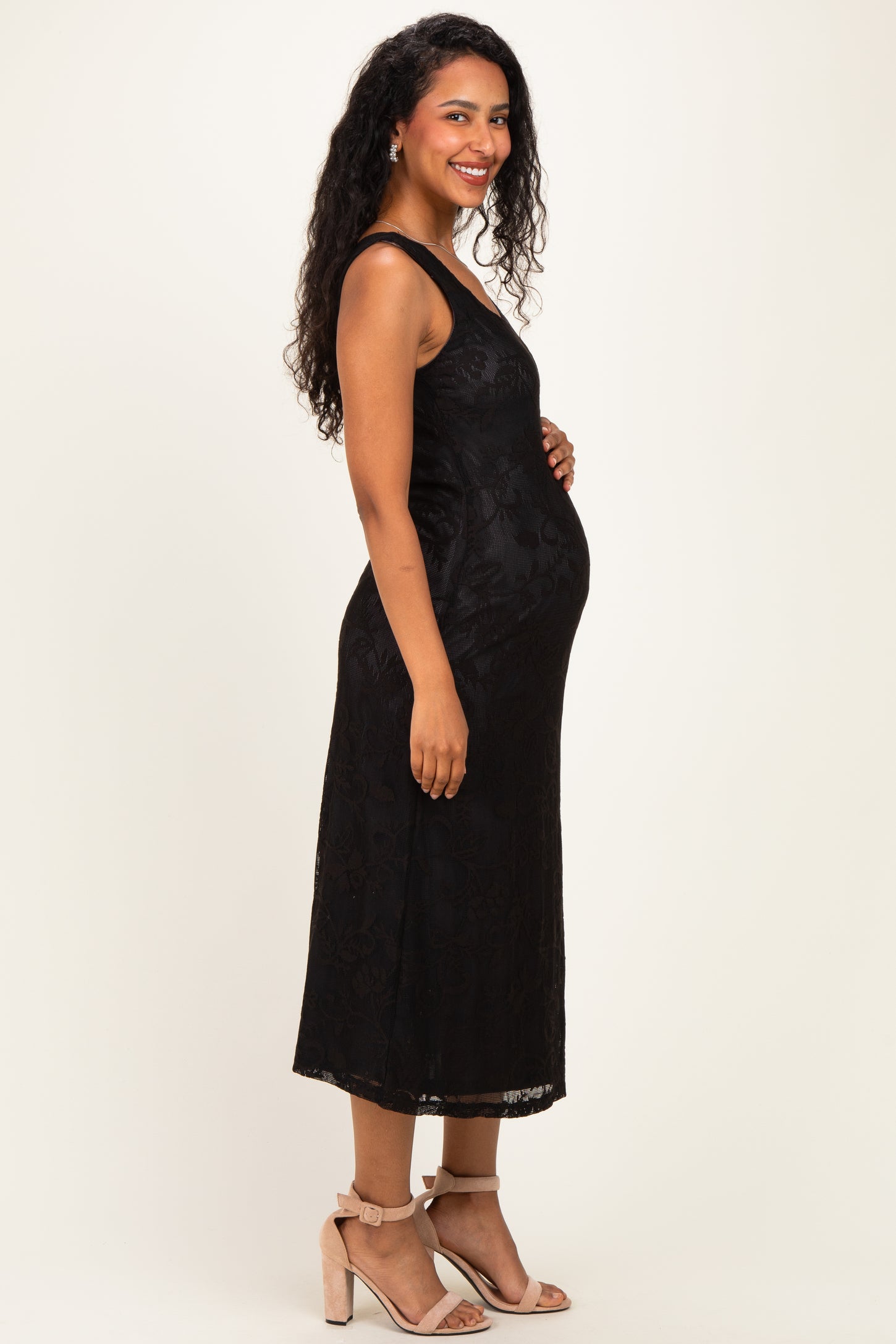woman wearing a black lace maternity dress and holding her baby bump