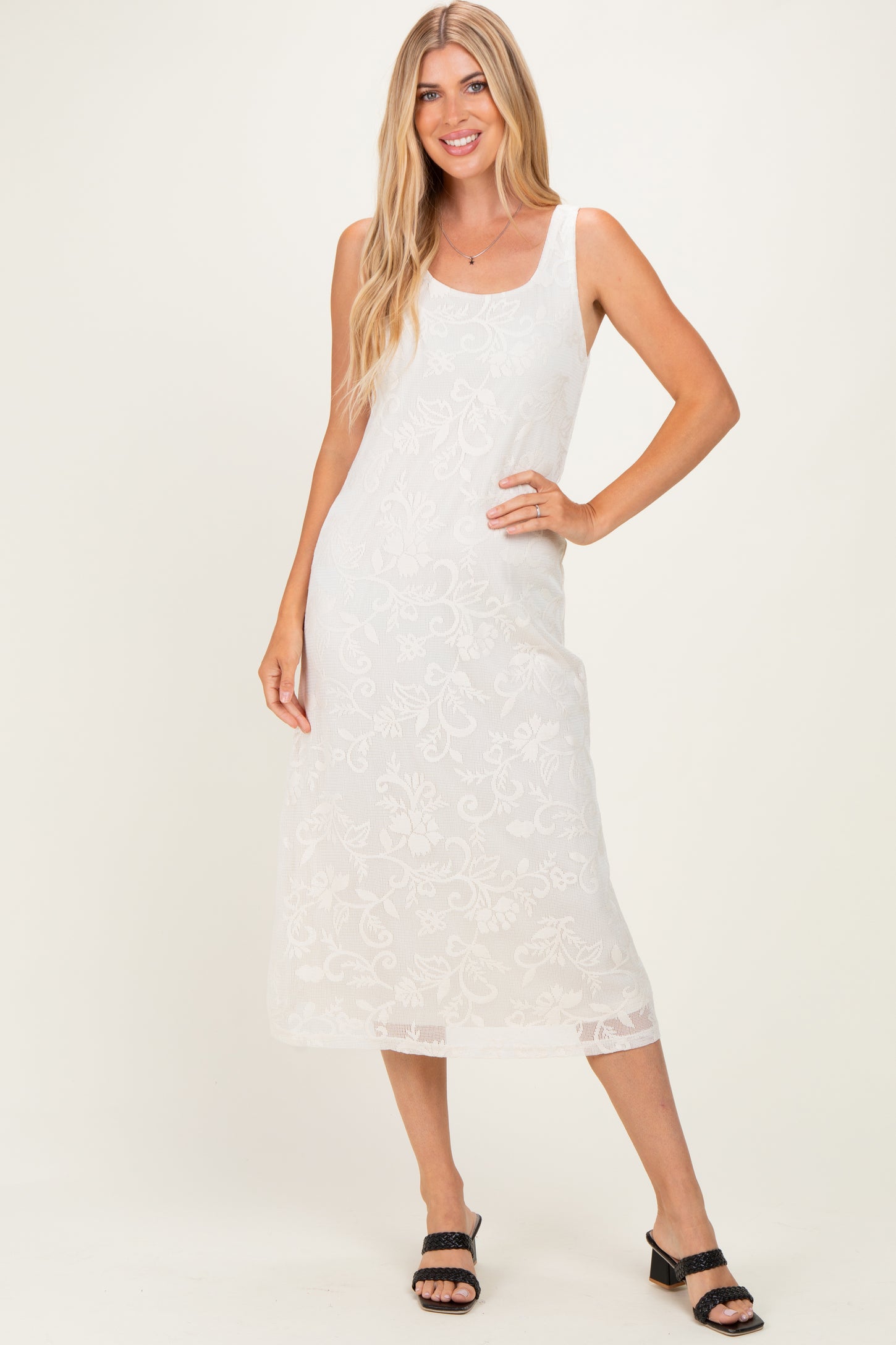 woman wearing a white floral lace midi dress with a square neckline and spaghetti straps