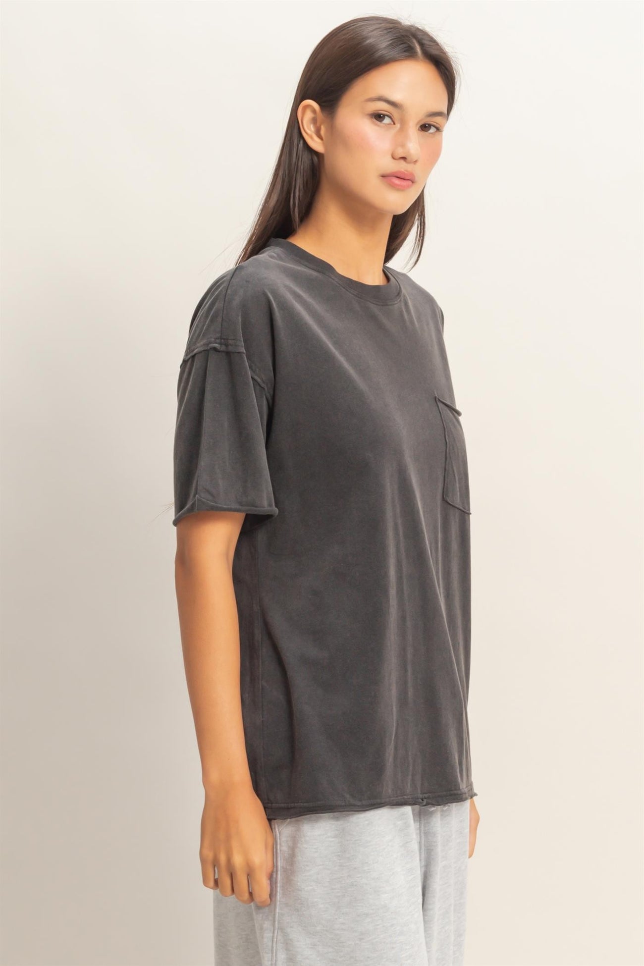 woman wearing a dark gray oversized t-shirt with a pocket and short sleeves