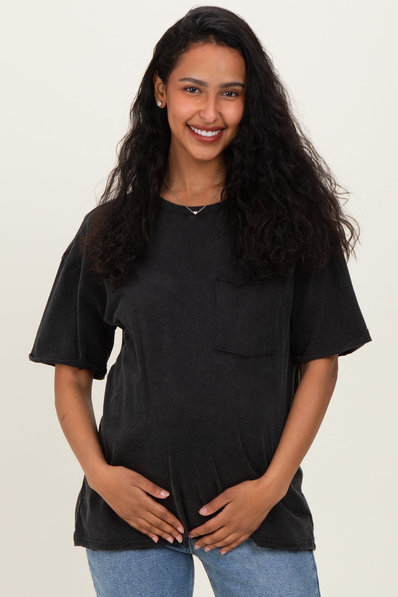 woman wearing a black oversized maternity t-shirt with a front pocket and holding her baby bump