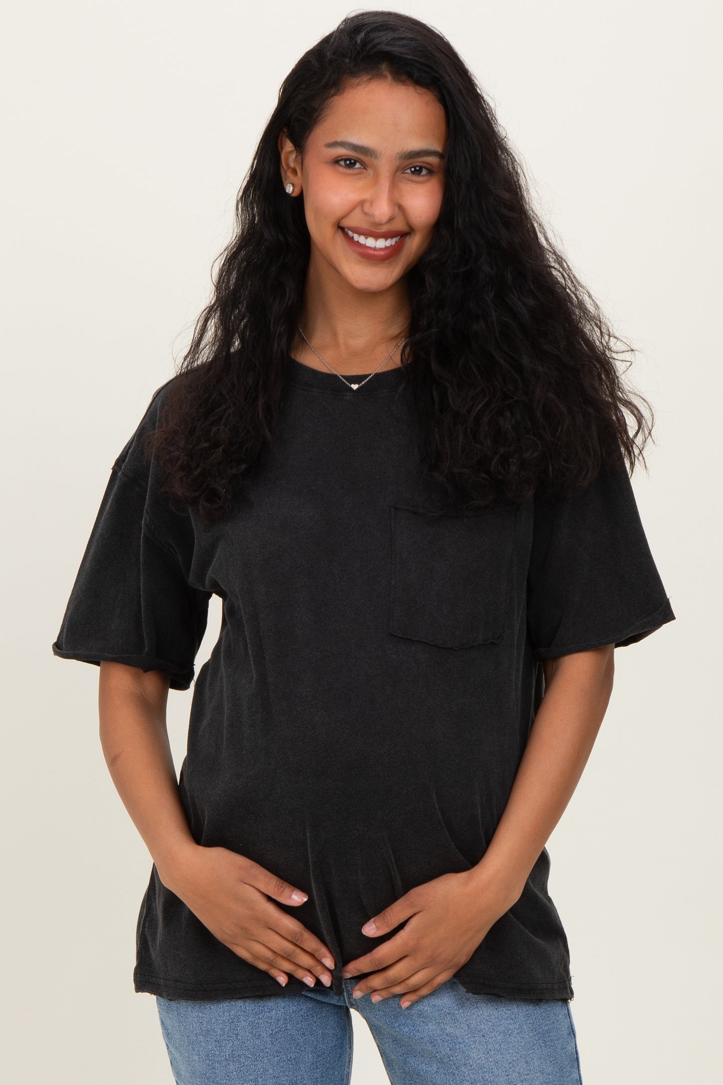 woman wearing a black oversized maternity t-shirt with a front pocket and holding her baby bump