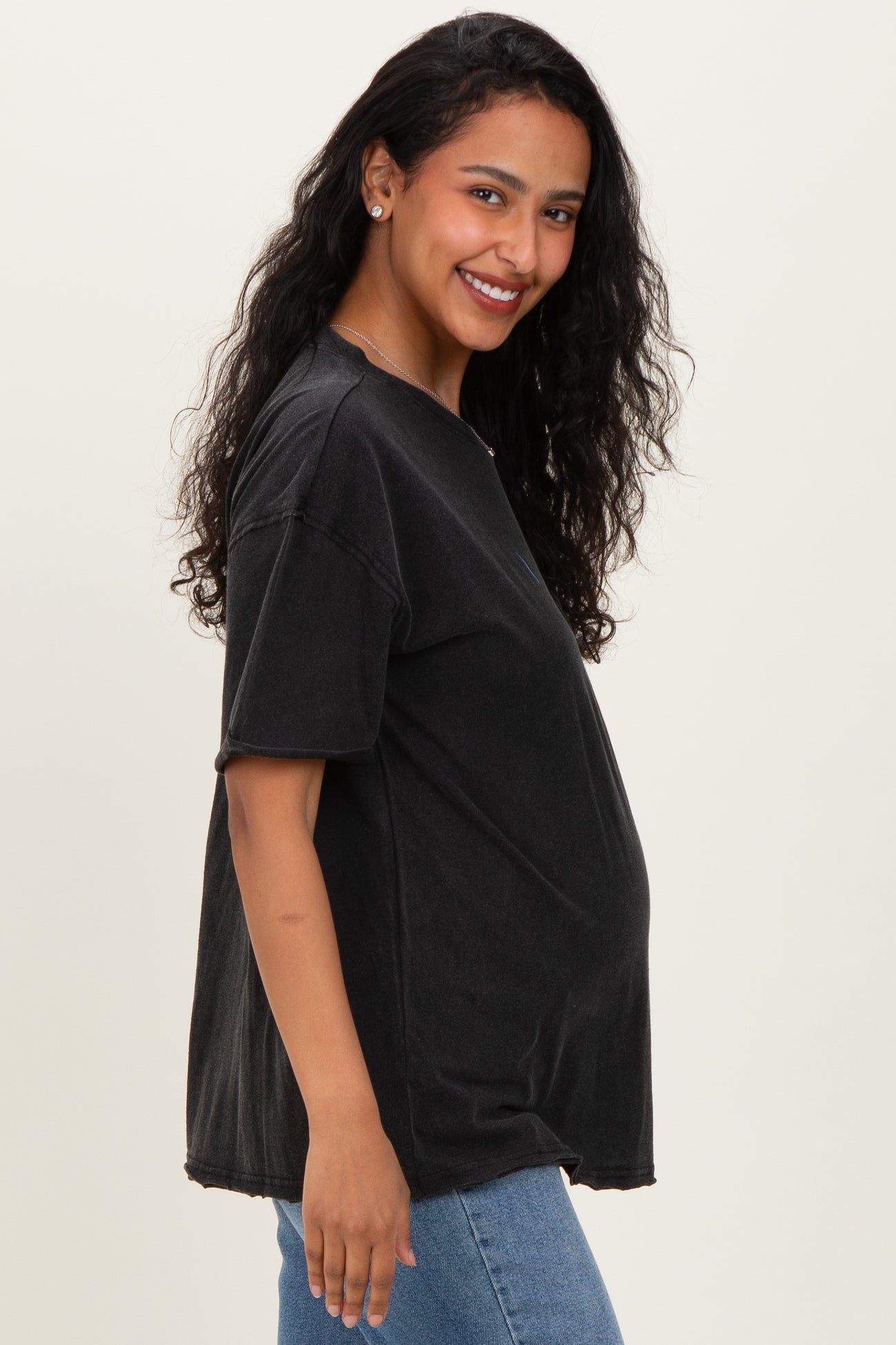 woman wearing a black oversized maternity t-shirt and showcasing her baby bump