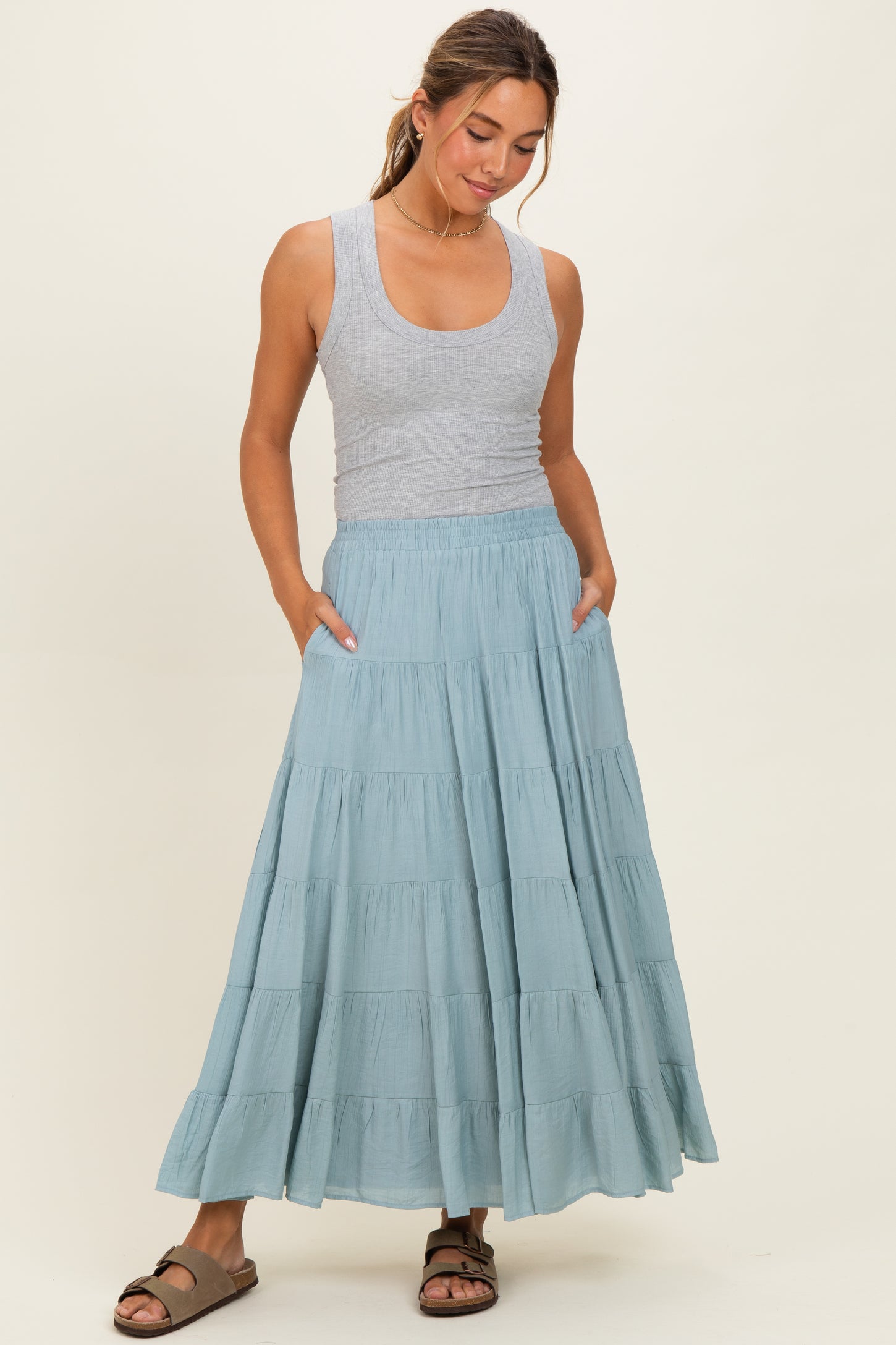 woman wearing a gray tank top and a flowy teal tiered maxi skirt with pockets