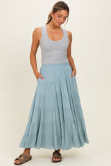 woman wearing a gray tank top and a flowy teal tiered maxi skirt with pockets