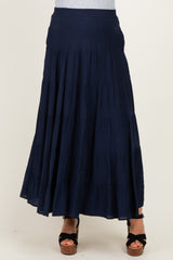 woman wearing a navy tiered maxi skirt, styled with a fitted top and strappy heels, showcasing a flowing silhouette