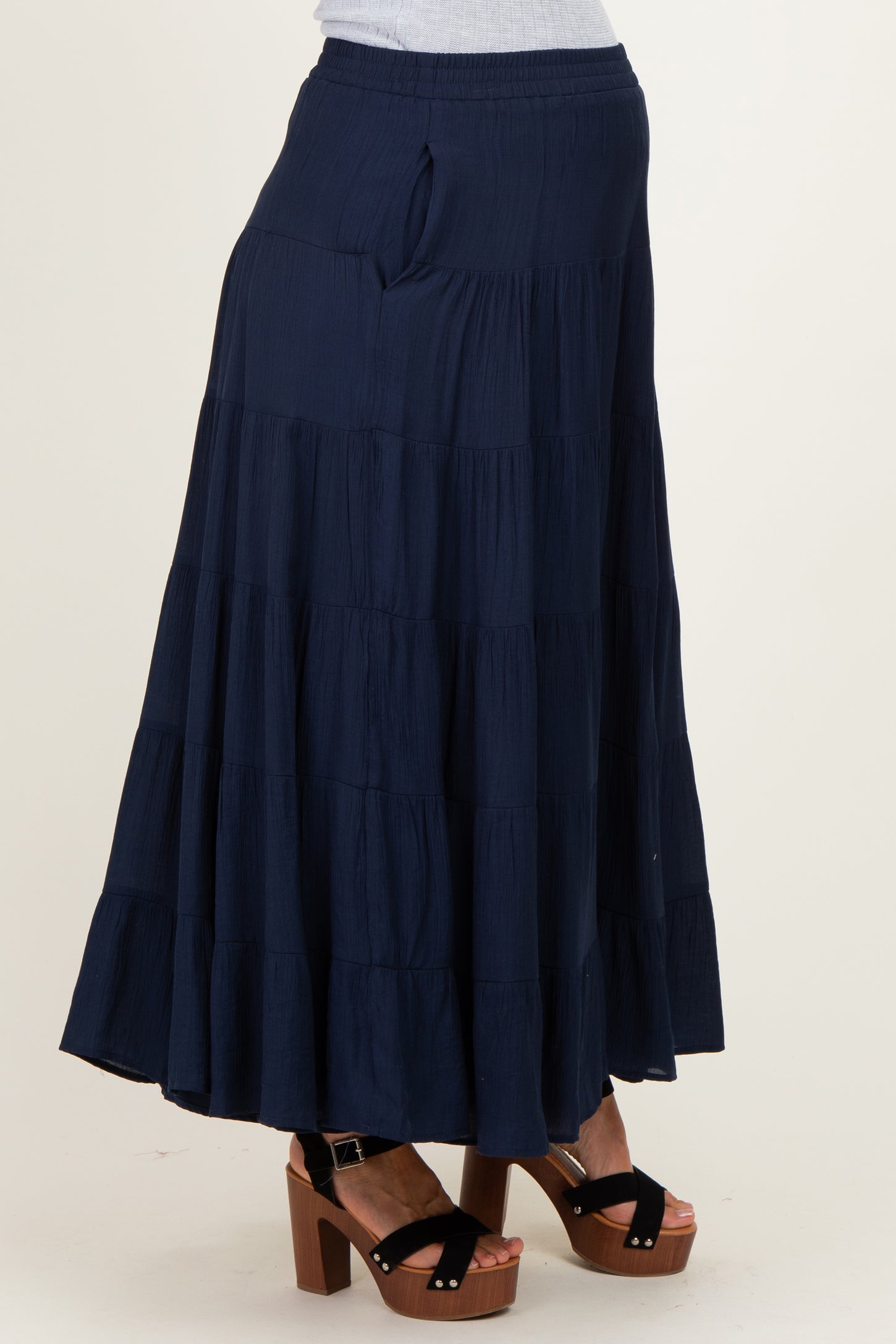woman wearing a navy blue tiered maternity skirt with pockets and paired with chunky heeled sandals