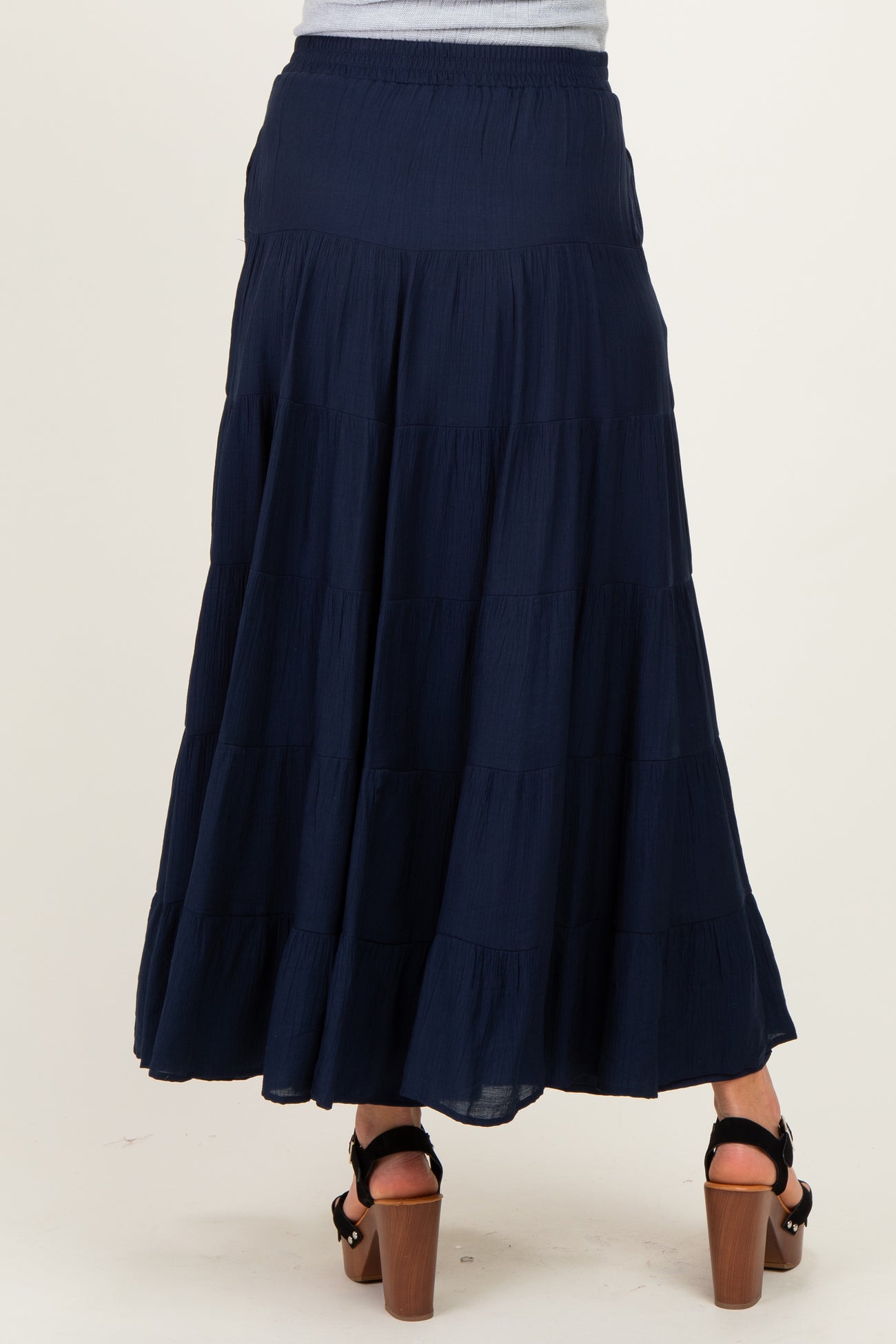 woman wearing a navy maternity maxi skirt with tiered ruffles, showing the back view and a relaxed fit