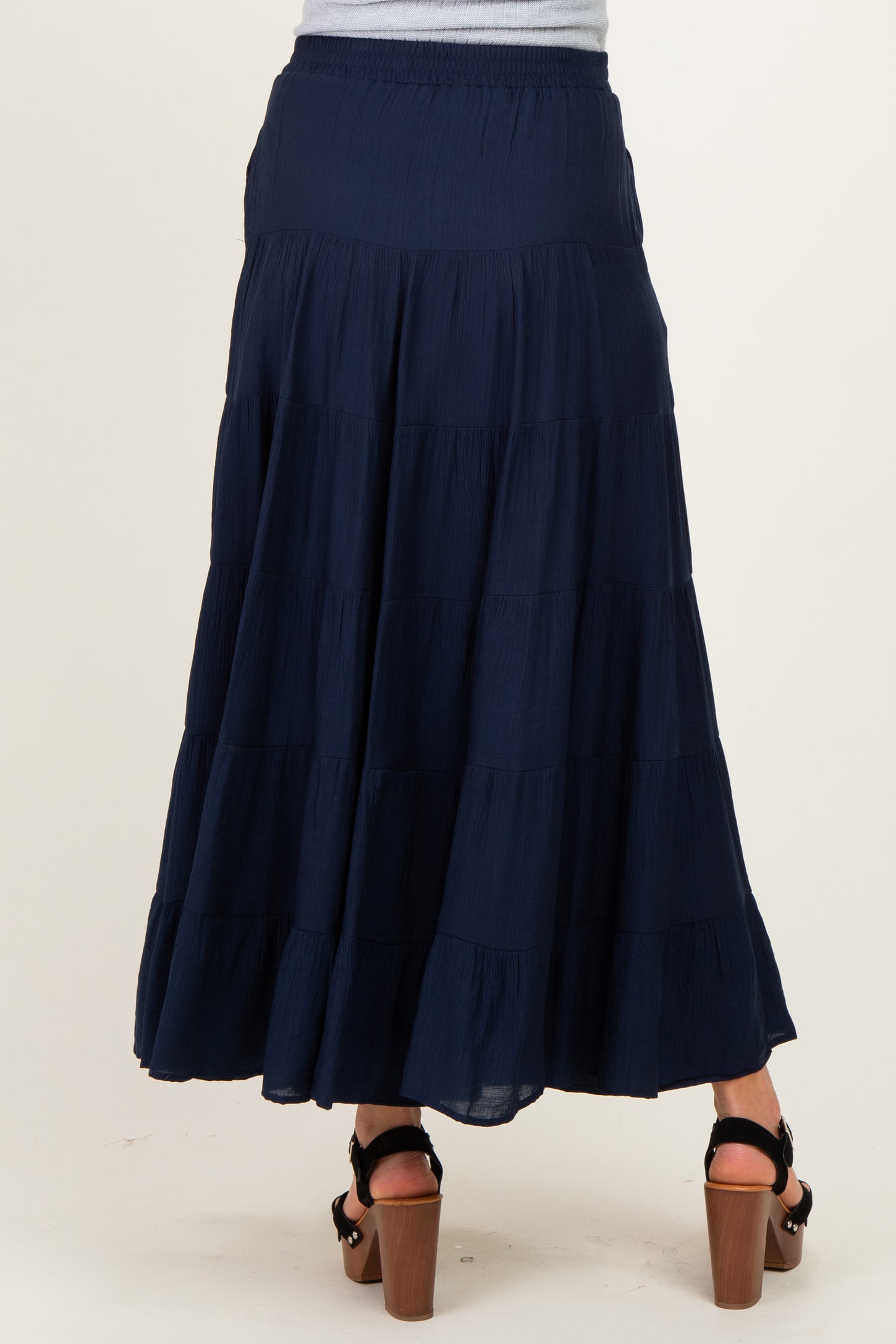 woman wearing a navy maternity maxi skirt with tiered ruffles, showing the back view and a relaxed fit