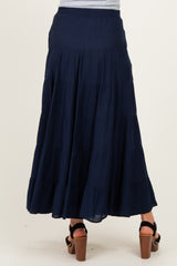 woman wearing a navy maternity maxi skirt with tiered ruffles, showing the back view and a relaxed fit