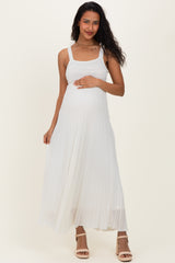 woman wearing a white pleated maternity dress and gently holding her baby bump