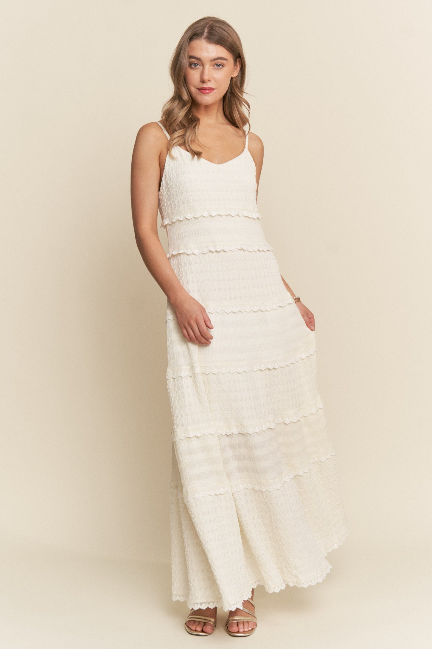 woman wearing a white tiered maxi dress with spaghetti straps and a textured fabric