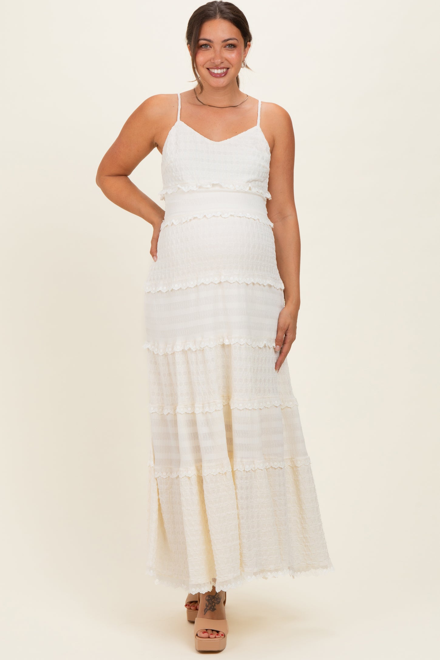 woman wearing a white tiered maternity maxi dress with adjustable straps and a visible baby bump