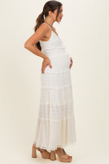 woman wearing a white tiered maternity maxi dress and holding her baby bump