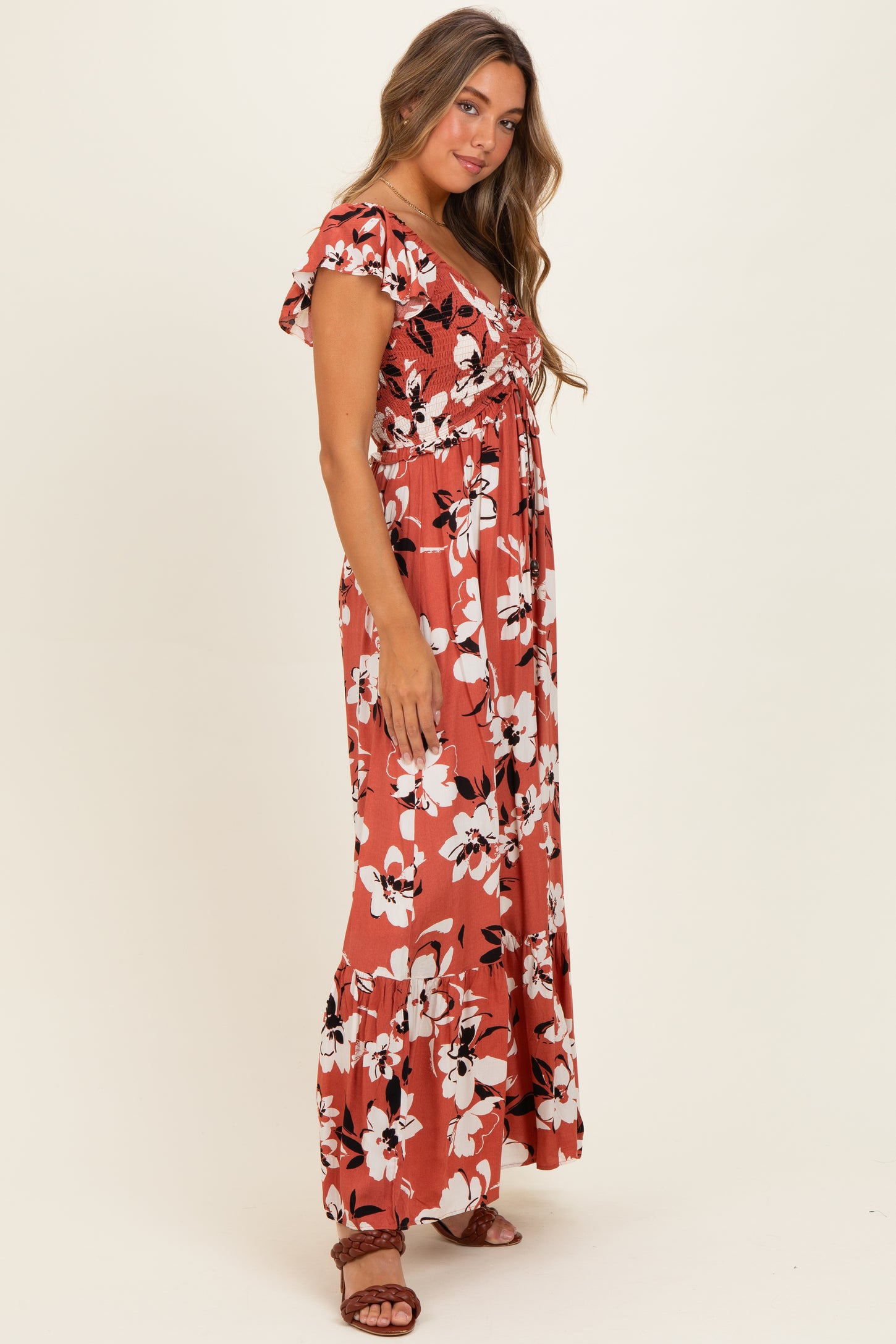woman wearing a rust floral maxi dress with short sleeves and a flowy skirt