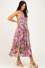 woman wearing a floral printed maxi dress with a plunging neckline and a flowy skirt, posing with one hand on her hip