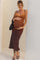 woman wearing a brown and mustard ombre maternity dress, cradling her baby bump against a backdrop