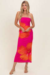 woman wearing a bright pink strapless maxi dress with large orange hibiscus flowers