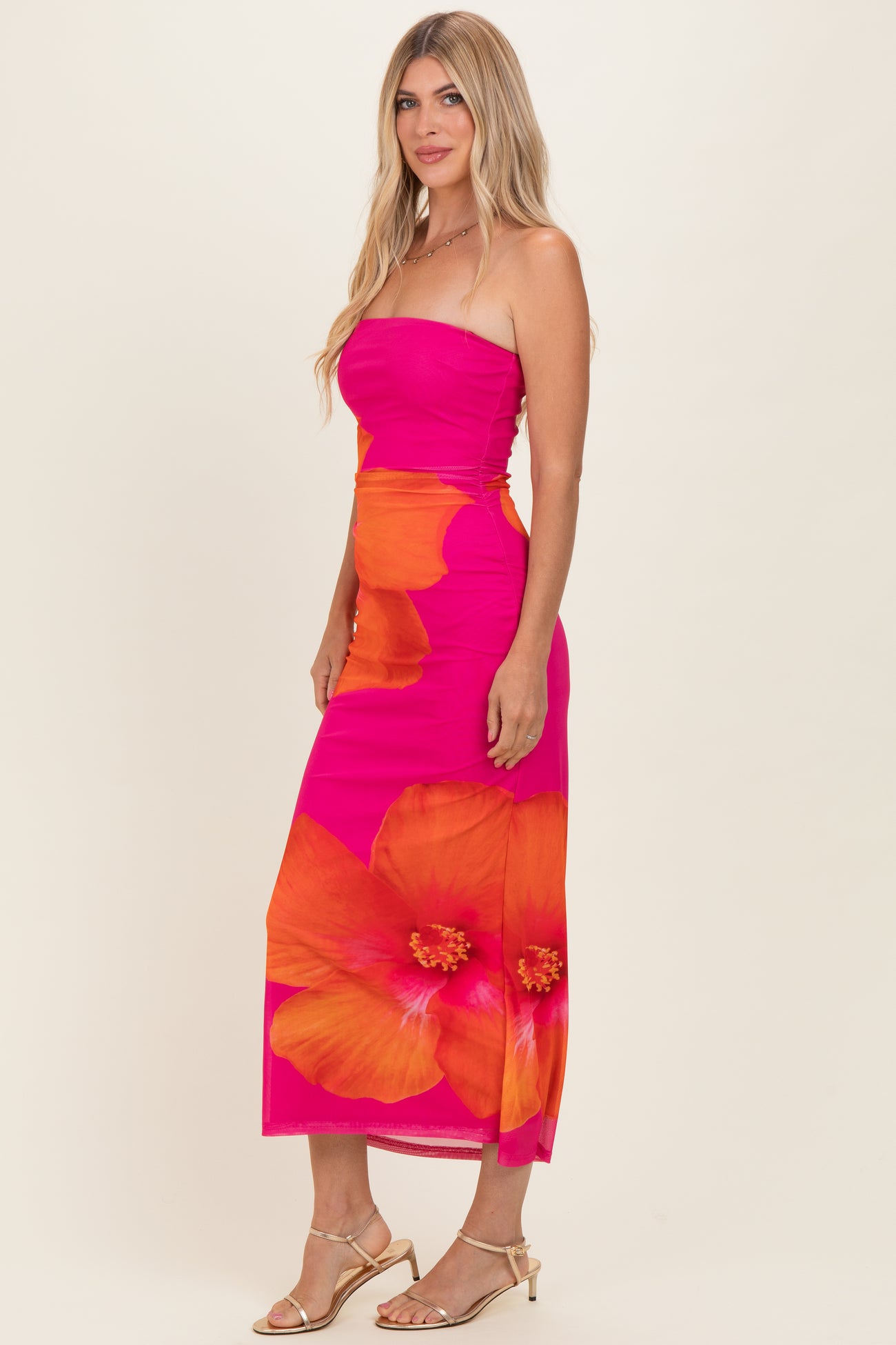 woman wearing a pink strapless midi dress with a floral print in orange and yellow