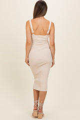woman wearing a beige ribbed midi maternity dress with adjustable straps, showing a fitted silhouette and back view