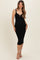 woman wearing a black ribbed maternity dress with a keyhole detail and a fitted silhouette standing and showing her baby bump